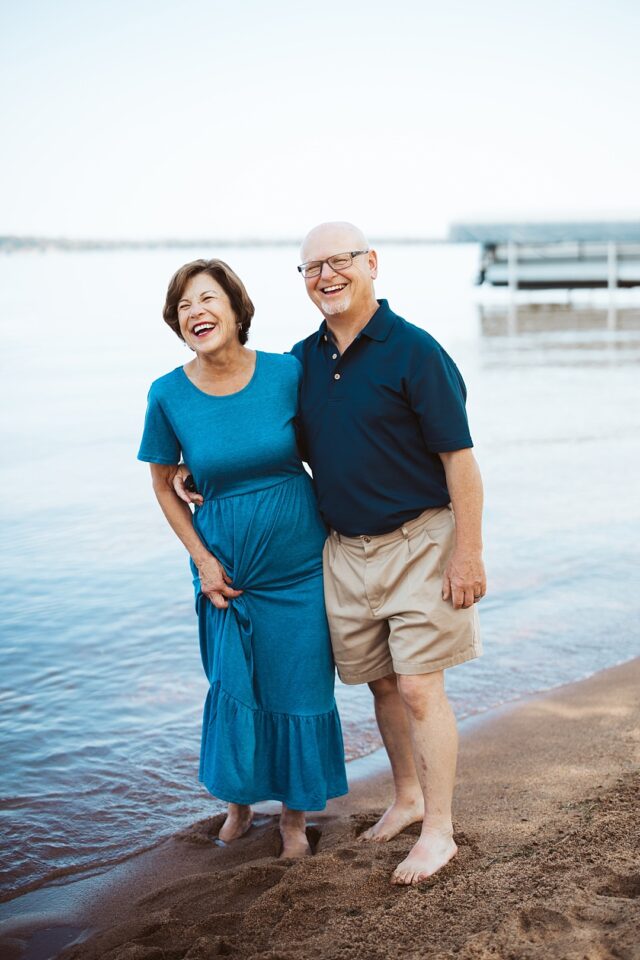 happy couple posing fora shoreline photo along Lower Whitefish Lake in Crosslake MN