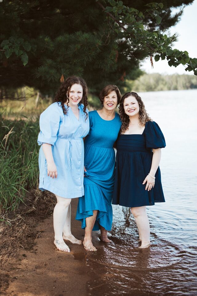 Mom and daughters posing for a family photo at Boyd Lodge. They are standing on the shoreline of Lower Whitefish Lake in Crosslake mn