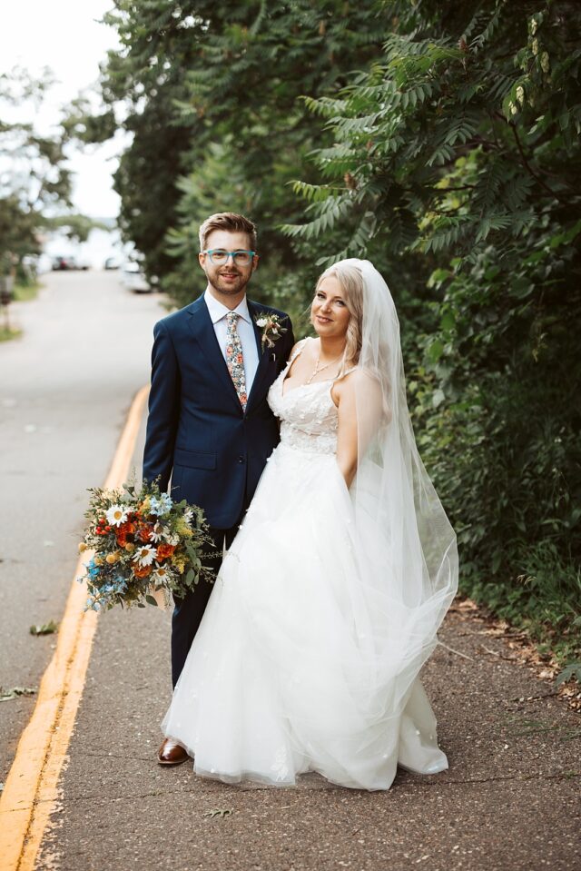 a groom and bride standing for an outdoor portrait on during their wedding day