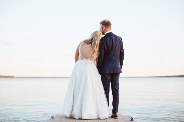 a bride and groom looking out at Gull Lake after their summer wedding day