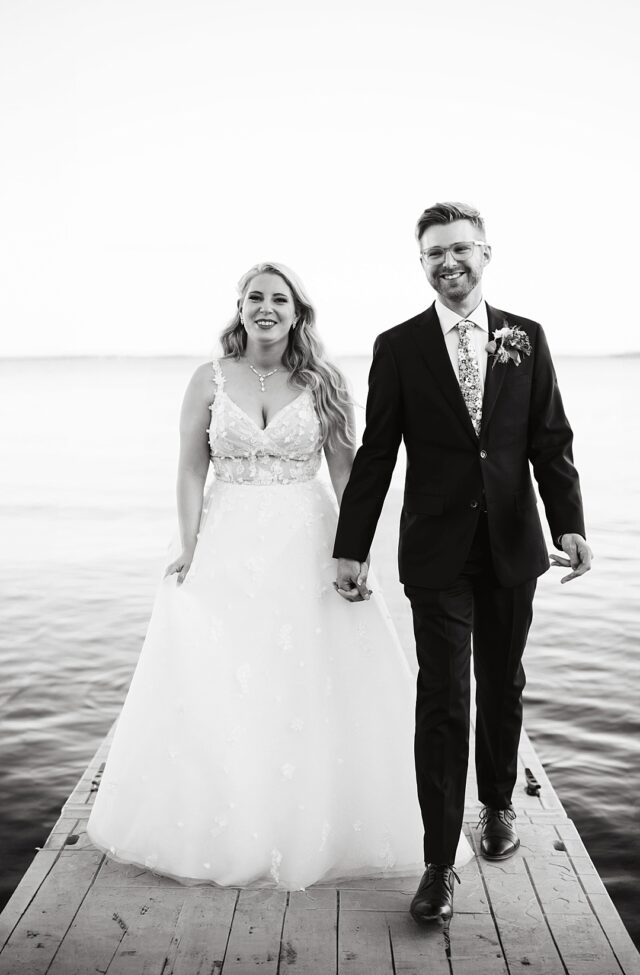 a smiling bride and groom walking on the dock at Grand View Lodge