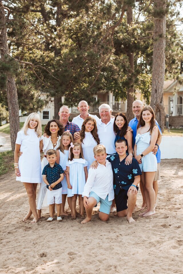 large family portrait on the beach at Maddens Resort. The family is wearing sun dresses and shades of blue. A perfect summer vacation portrait on Gull Lake